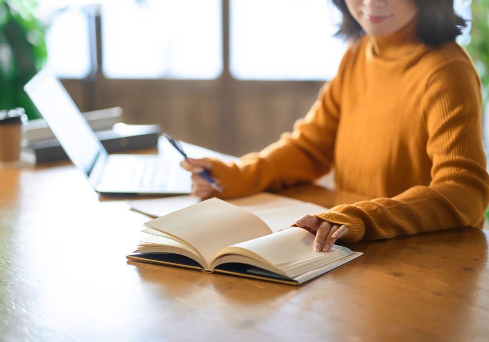 student using a laptop and a notebook